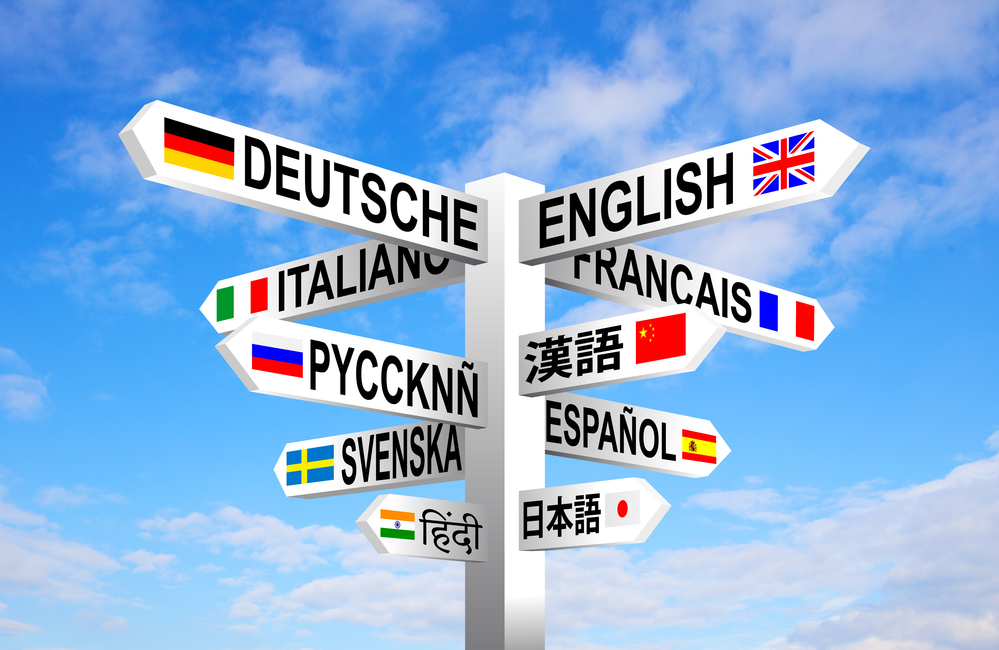 תרגום מסמכים במגוון שפות ותחומים בתמונה: סימני דגלים על עמוד מכוונים על רקע שמים כחולים