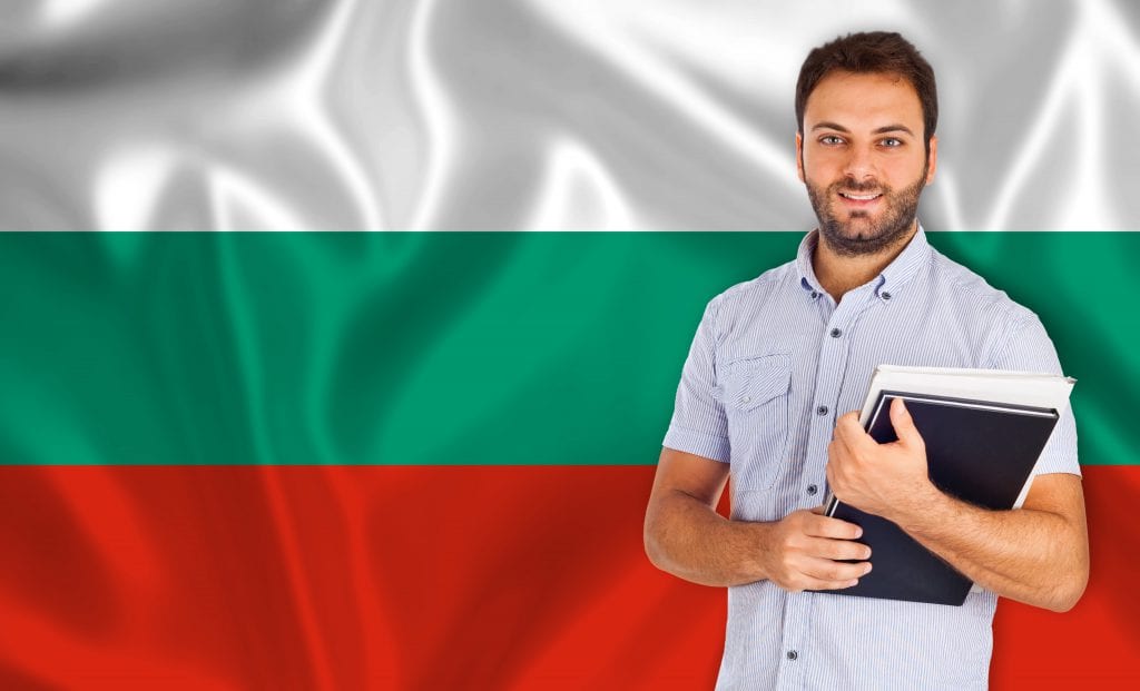  תרגום לבולגרית מאנגלית או עברית בתמונה: מתרגם מחזיק קלסר שחור על רקע דגל בולגריה לבן ירוק אדום