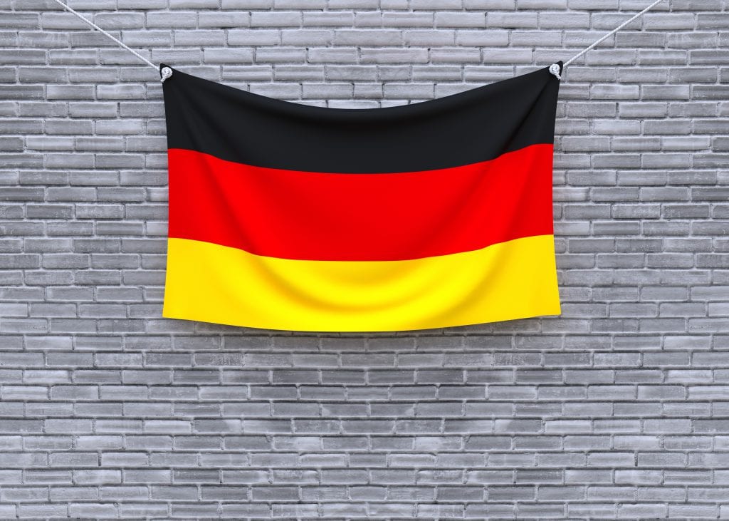 תרגום לגרמנית בתמונה דגל גרמניה על רקע חומת לבנים
