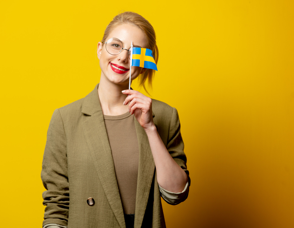 תרגום לשוודית בתמונה אישה צעירה אוחזת דגל שוודיה 