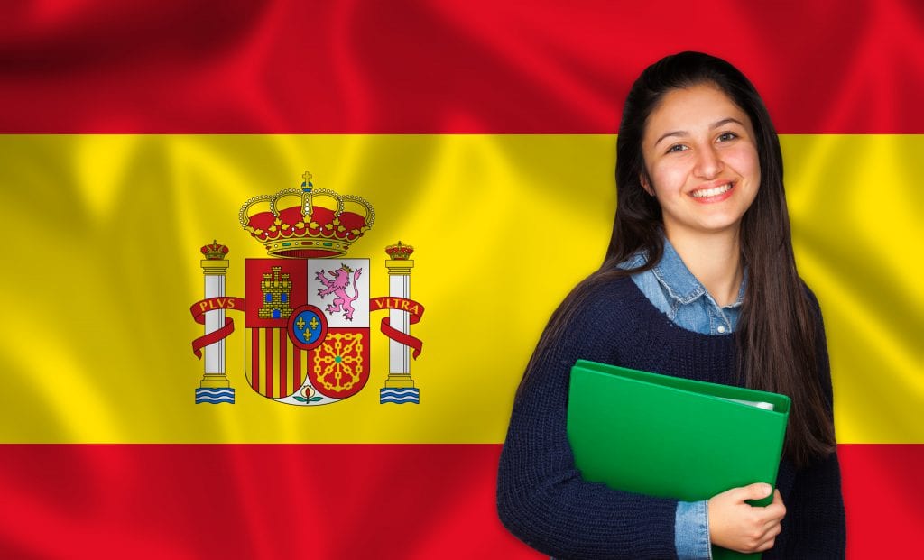 תרגום מסמכים לספרדית .בתמונה מתרגמת אוחזת קלסר ירוק על רקע דגל ספרד