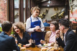 תרגום תפרטים למסעדות בתמונה מלצרית לוקחת הזמנות מאנשים במסעדה